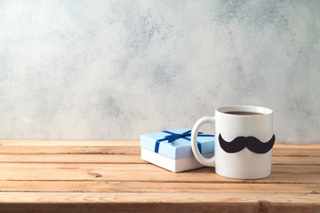 Happy Father's day concept with coffee mug and gift box over wooden background