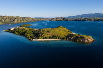 Seen from a bird's eye view, an idyllic island is surrounded by a healthy coral reef in Komodo National Park, Indonesia. This tropical area is known for its marine biodiversity as well as its dragons.