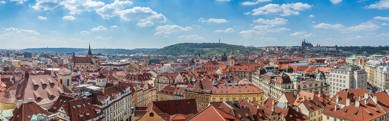 Obraz premium Outdoor sunny panoramic aerial top view of Prague old town cityscape, Charles Bridge tower and background range of mountain with Castle, St. Vitus Cathedral and Petrin tower in Prague, Czech Republic.
