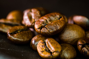 Brown roasted coffee beans on black background, close up, macro