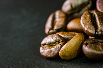 Brown roasted coffee beans on black background, close up, macro