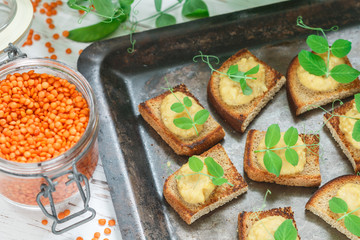 Fototapeta na wymiar Delicious bread toast with hummus (pate, pasta, dip) of lentils and carrots with pea sprouts. Healthy breakfast. Selective focus