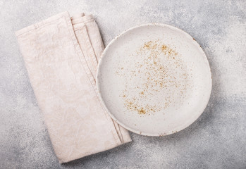 Cooking background with empty light plate and linen napkin on grey concrete table. Rustic style. Selective focus. Top view, copy space