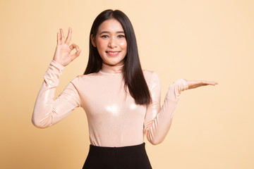 Beautiful young Asian woman show palm hand and OK sign.