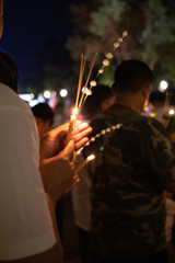 Unidentify people with lighted candles in hand during Buddhist ceremony.