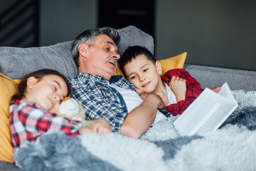Grandfather and grandchildren reading a book. Reading fairy tails.
