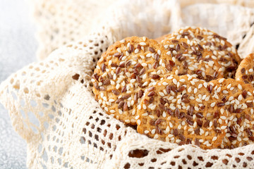Concept of healthy nutrition: fitness cookies with sesame seeds in a wicker napkin plate. Light background.