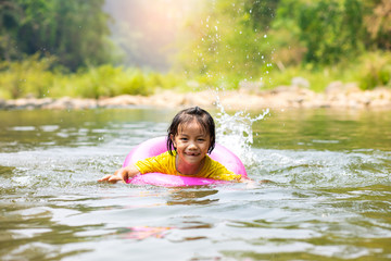 Little Asian girl in pool ring swimming in  river