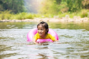 Fototapeta premium Little Asian girl in pool ring swimming in river