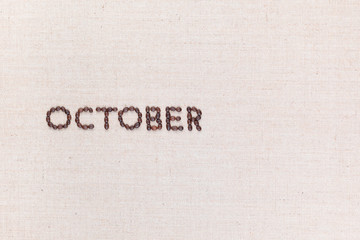 The word October written with coffee beans shot from above, aligned to the left.