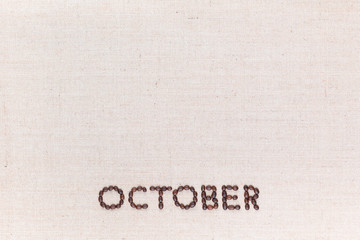 The word October written with coffee beans shot from above, aligned at the bottom.