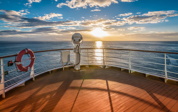 Wooden deck and railing from cruise ship. Beautiful sunset and ocean view.