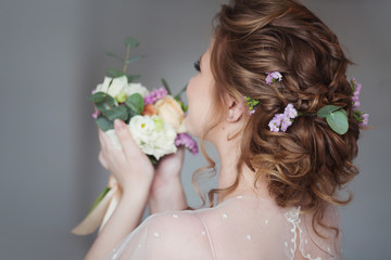 Obraz na płótnie Canvas Beautiful and elegant wedding hairstyle. Young bride with bouquet of flowers