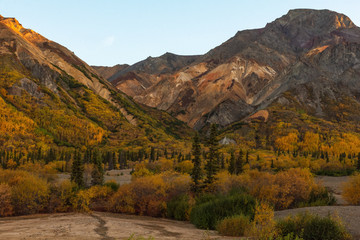 Fall colors mix yellow with the evergreen of a mixed forest covering the gravel slopes of small mountains