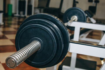 bar for power lifting with metal discs lies on the rack in the gym. training tools