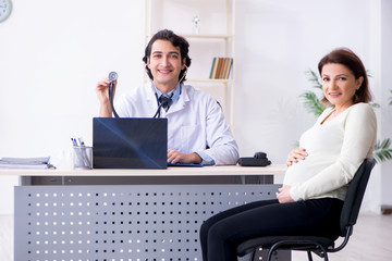 Old pregnant woman visiting young male doctor 