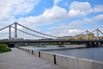 Fototapeta premium Moscow, Russia - May 13, 2019: Crimean Bridge (Krymsky Most) across the Moskva river against the blue cloudy sky. The view from the embankment
