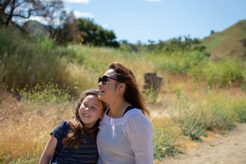 Woman and daughter standing and laughing together while playing in a stream or river