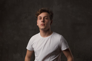 Handsome young man with a stylish haircut in a white shirt on black background looking at camera.