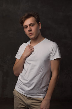 Handsome young man with a stylish haircut in a white shirt on black background looking at camera.