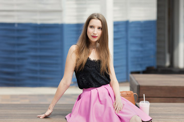 Young beautiful girl with long hair drinks fruit smoothie.