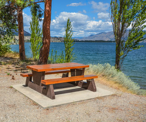 Obraz premium Picnic area with table and benches on a shore of Okanagan lake