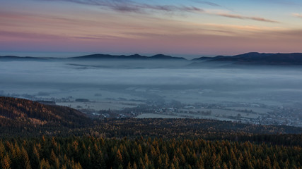 Obraz premium Sunrise above the town, which is covered by fog. The rock in foreground.