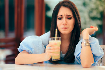 Woman Tasting Sour Lemonade Drink in a Restaurant - obrazy, fototapety, plakaty
