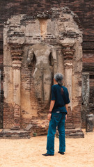 Obraz na płótnie Canvas Senior asian traveller looking up to a buddha ruin in Sri Lanka