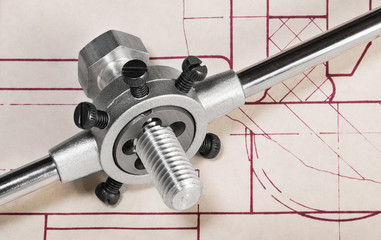 Threading die in tap wrench on technical drawing detail. Steel cutting tool when working thread on metal bolt shaft. Metallic parts on plan draft. Chip machining in mechanical engineering. Metalwork.