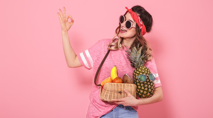 Portrait of a girl with healthy food, fruits, on a pink background