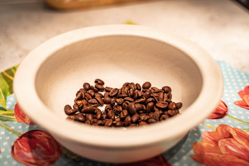 Coffee beans in wood bowl on flower background (selective focus)