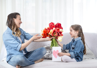 Fototapeta na wymiar Mother's day. Little daughter with flowers congratulates her mother