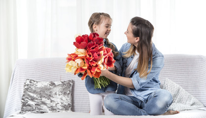 Mother's day. Little daughter with flowers congratulates her mother