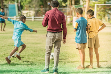 Asian boys practice kicking the ball to score goals in the public football field.