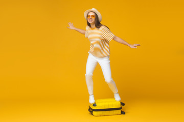 Full-length picture of European girl isolated on background standing on suitcase showing that she is ready for flying abroad