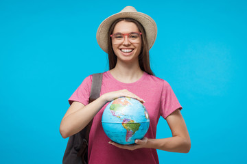 European Caucasian female isolated on blue background with globe in hands symbolizing readiness for travelling abroad