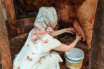 woman milkmaid milking a cow, farm