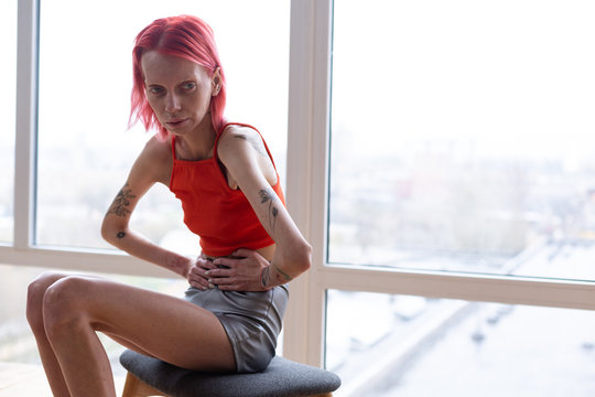 Woman with anorexia sitting near the window feeling awful