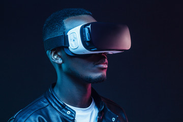 African American man standing at night with VR headset on