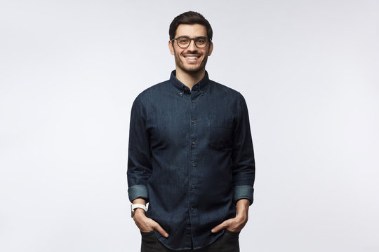 Handsome smiling european guy in casual denim shirt standing against white background