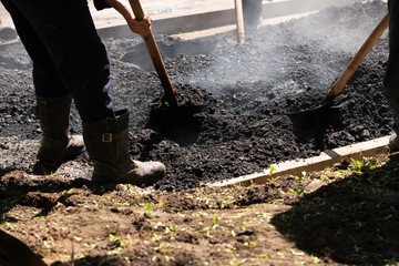 Road Builders laid Asphalt-Teamwork. Asfaltobetonnye work on. d. Hot asphalt gravel, level workers.