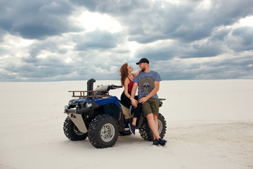 Obraz premium girl hugs her boyfriend on a quad in the desert, a loving couple enjoys each other