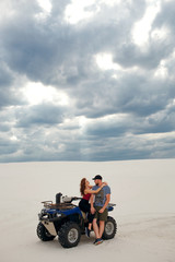 Obraz premium girl hugs her boyfriend on a quad in the desert, a loving couple enjoys each other