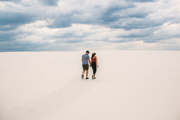 the girl and the guy are walking in the desert, the couple in love holds each other's hands, but they are lost in the desert