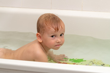 Little boy 3 years old bathes in the bath