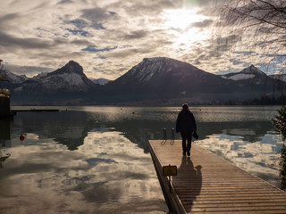 Vistas del lago Wolfgangsee con una persona en la plataforma reflejada en el agua, invierno de 2018