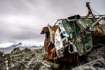 Shipwreck on norwegian coast in fjord with mountain.