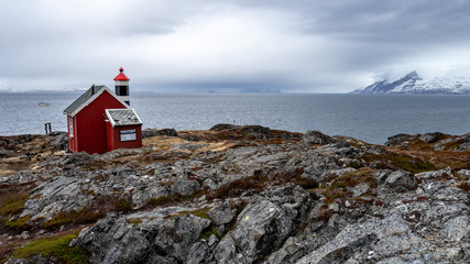 Red house and lighthouse in norwegian fjord.