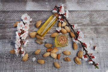 Natural almond oil in almonds and bottle of almond trees on the wooden background.